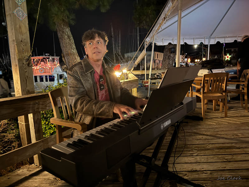 Christopher Siren playing piano outdoors on the deck at the Tiki bar in Oriental, NC